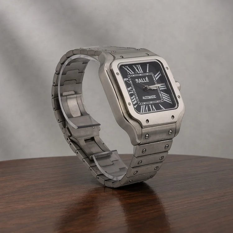 Close-up of Ralle Legacy Silver Automatic Watch with Black Dial on polished wood surface.