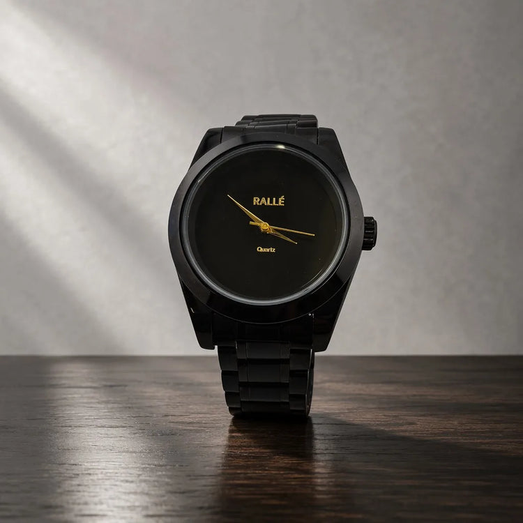 Rallé Men's Pure Time Black Case - Front view on dark wood surface showing minimalist matte black dial with gold-tone hands and black metal bracelet, reflecting refined craftsmanship and premium detail.